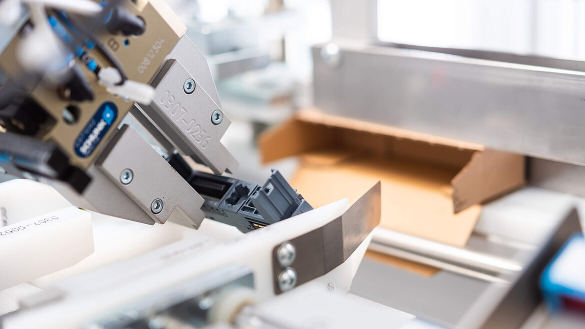 Close-up of a packaging machine with a folding box