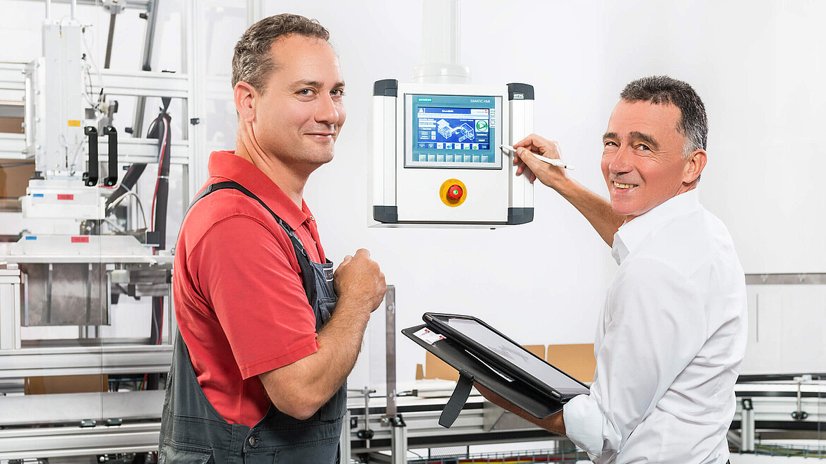 Two employees at a packaging machine’s controller